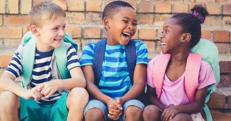 three children sit together and laugh