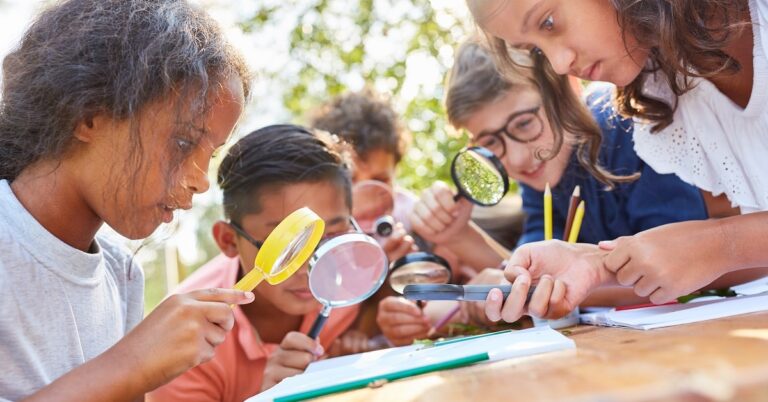 young learners looks at something outside through magnifying glasses