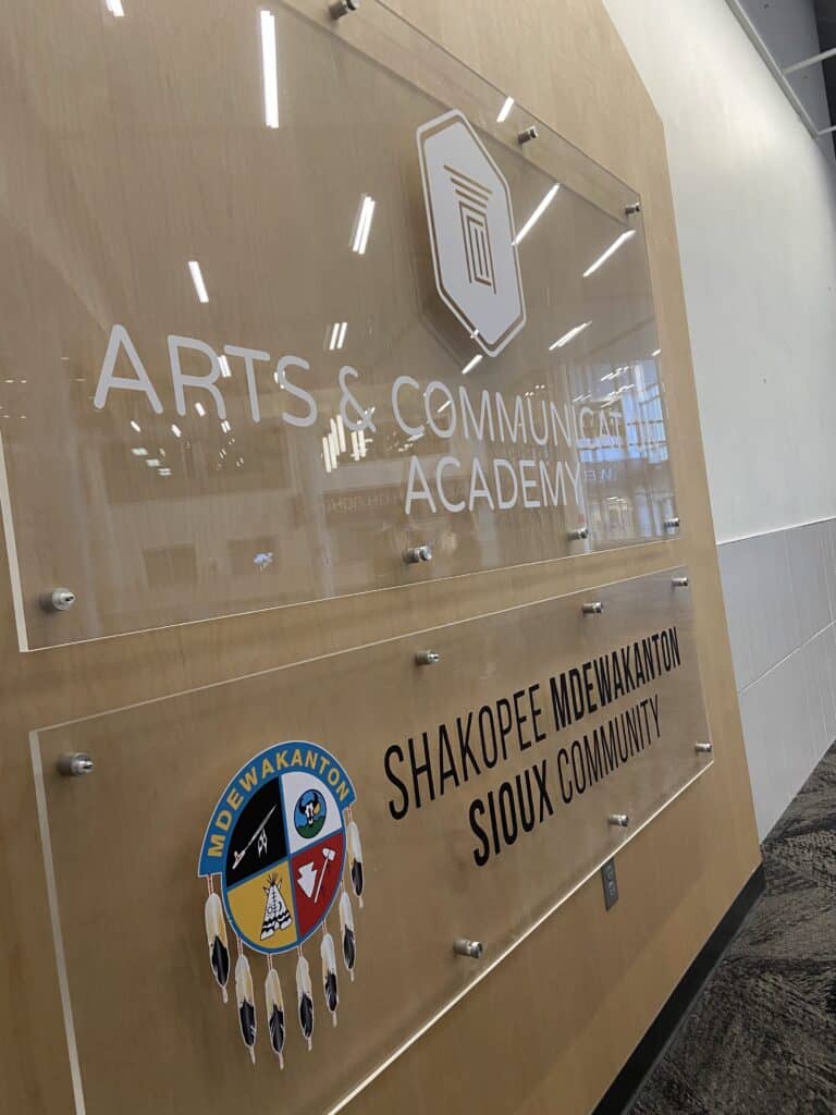 One sign reading "Arts & Communications Academy" and a sign below reading, "Shakopee Mdewakanton Sioux Community"