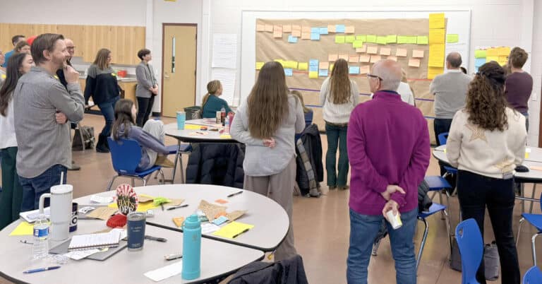 People gather around a wall of sitcky notes.