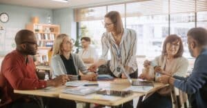educators gather in groups around tables in a classroom for planning