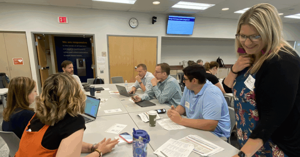 A group of adults sit at a table, attentive to one.