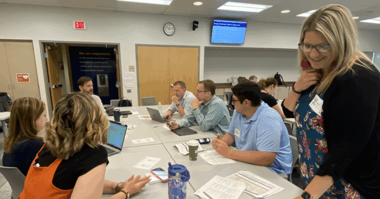 A group of adults sit at a table, attentive to one.