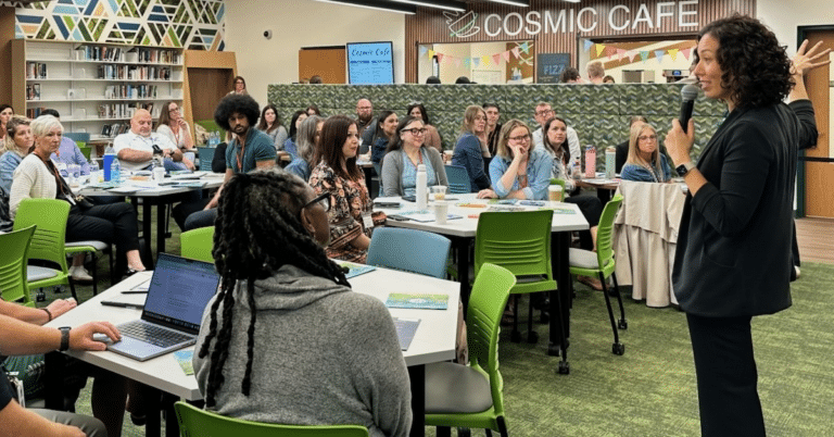 A group of educators gathers in a school library and cafe for whole-group activities