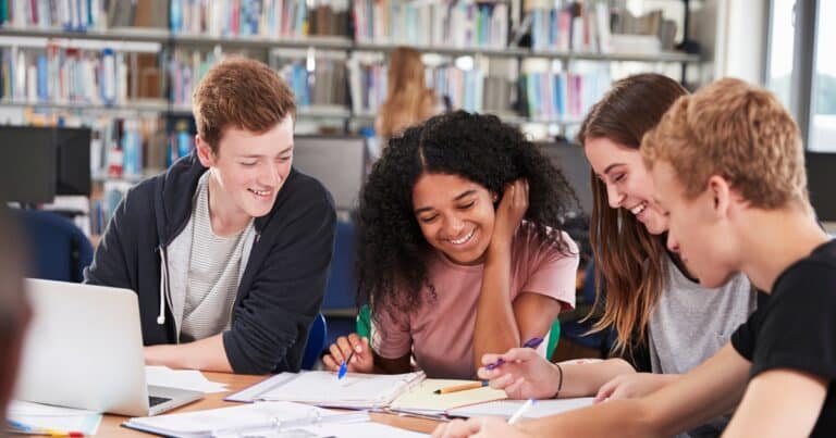 teens in a library at a table looking at papers