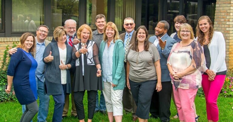A group of people of varying ages pose for the camera in front of a building