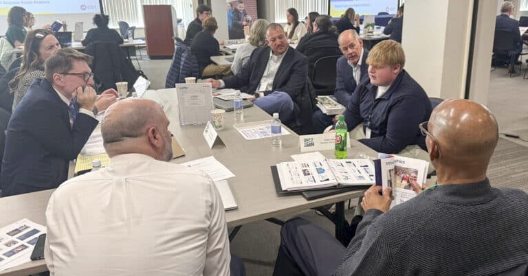 people at tables listneing to a student speak