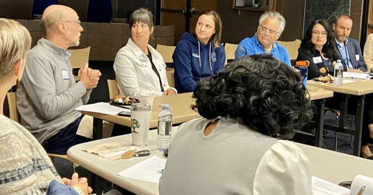 Adults gather at tables speaking with each other in a school
